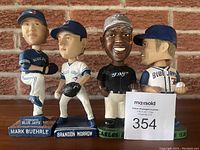 Front view of the four Blue Jays bobbleheads standing side by side on a brick background.