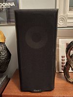 Front view of one speaker showing black fabric grille with Mission logo at bottom.