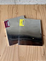 Pair of Lamborghini magazines with metallic gradient covers and barcode stickers on a wooden surface.