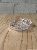 Clear glass dish with etched tulip floral design photographed on a wooden surface.