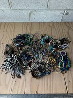 Top view showing the entire lot of mixed costume jewelry spread out on a wooden surface.