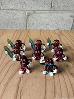 Group photo showing eight California Raisin Man plastic figurines in various poses with surfboards and different colored sunglasses and shoes.