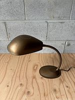 Side view of vintage MCM cobra shade goose neck desk lamp showing bronze finish and curved design.