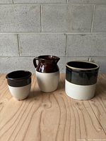 Full view of the three pottery pieces: jug, smaller crock, and larger crock with hairline crack.