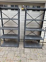 Two black metal shelving units side by side outdoors, showing overall structure and size.