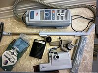 Photo showing top and side view of the Arrus Lux5500 canister vacuum cleaner with hose, metal extension wand, brush and upholstery attachments, power cord, and Electrolux filter bags.