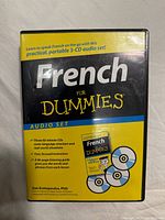 Front cover of the French For Dummies 3-CD audio set in its plastic case. Yellow and black design with summary of contents on the front.