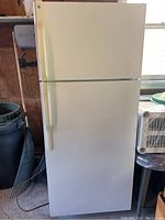 Front view of GE white refrigerator freezer, showing closed doors and side handles.
