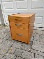 Full front view of the beech finish drawer unit with handles and casters visible.