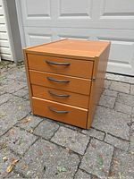 Front view showing four drawers with metal handles and lock on side.
