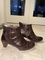 Side angled view of brown leather ankle boots showing overall condition and shape