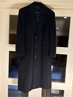Front view of dark navy men's wool overcoat hanging on hanger, showing notch lapels, button closure, and flap pockets.