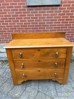 Front view of the vintage pine chest of drawers showing three drawers with brass drop pulls and aged wood finish.