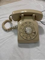 Front angled view showing rotary dial, handset and body with beige finish on white background