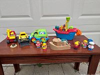 Entire lot showing Sesame Street camper van, pirate ship, wooden boat, character figures, and construction trucks.