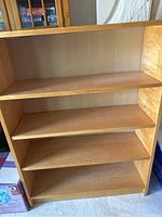 Front view of the wooden bookshelf showing four interior adjustable shelves and overall structure.