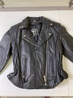 Front view of black women's leather jacket with zipped front, collar snap buttons, and ruched side panels.