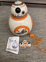 Full view of 2017 Spin Master BB-8 droid with remote, charger, and instruction manual on carpeted floor.