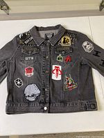 Full view of front of denim jacket showing multiple Star Wars patches including Death Star, Sith, Vader, Celebration, and others.