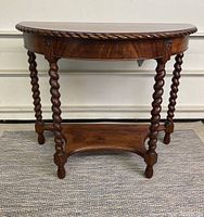 Front view of the half moon table showing barley twist legs and rope carved edge on table top.
