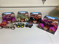 Lot of 7 monster trucks including 4 large Spin Master Monster Jam trucks (3 boxed, 1 out of box) and 3 small Hot Wheels mini monster trucks and 1 metallic Street Creeper truck with spikes