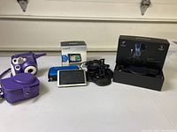 Polaroid 300 instant camera in purple with carrying case, Garmin Nuvi 1450 LMT GPS device, and Tonor TC-777 microphone with accessories on table.
