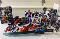 Photo showing assorted Power Rangers action figures, large vehicles, robot figures, and a large sword toy.