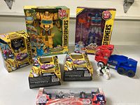 Full lot showing six Transformers toys in original packaging and two loose vintage style plastic trucks
