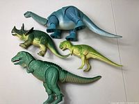 Four vintage dinosaur toys arranged on a white background showing top-side views and scale