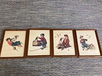 Four framed Norman Rockwell style prints laid horizontally on carpet showing young boys with dogs.