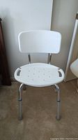 Front view of the white plastic bath seat with metal legs and rubber feet.