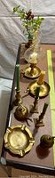 Brass vases, candlesticks, and ashtray arranged on table showing variety and detail