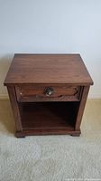 Front view of Kroehler wood veneer night stand showing drawer and open shelf below.