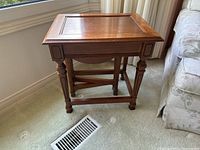 Larger wooden nesting table showing overall front and side view with carved legs and rectangular top