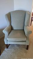 Front view of pale green upholstered wingback chair showing overall design and style