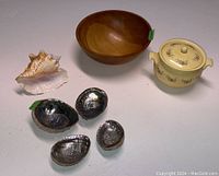 View of all items in the lot including the wood bowl, ceramic pot, large conch shell, and four abalone shells arranged on a surface.