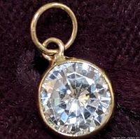 Close-up front view of the round moissanite pendant set in 10k gold bezel.