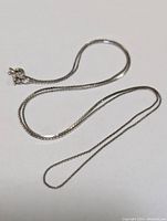 Full view of the 14K white gold box chain laid out on white background