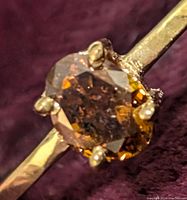 Close-up top view of oval yellowish brown diamond in six-prong 10K yellow gold setting.