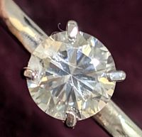 Close-up of the round moissanite gemstone in four-prong 10K gold setting, highlighting clarity and cut of the stone.