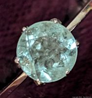 Close-up top view of round cut emerald showing inclusions and faceting