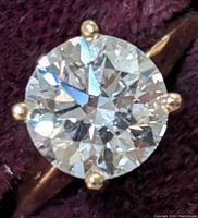 Top-down close-up of round brilliant diamond and six prongs in yellow gold band