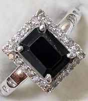 Front-facing view of ring showing rectangular centre gemstone and surrounding diamond halo