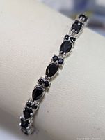 Close-up view of sapphire bracelet showing pear-shaped and round sapphires set in sterling silver.