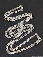 Full length view of the sterling silver chain necklace placed on a black background showing the entire chain and clasp.