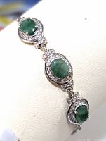 Close-up of the central emerald stone and surrounding cubic zirconia on sterling silver bracelet.