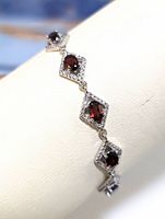 Close-up image of bracelet showing garnet stones set in diamond-shaped frames with cubic zirconia accents