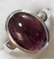 Close-up of sterling silver ring with large oval garnet cabochon stone.