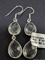 Close-up view of one sterling silver green amethyst double pear-shaped dangle earring showing faceted stones and hook closure.