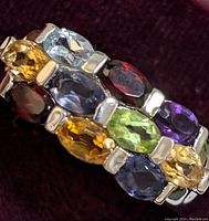 Close-up view of the sterling silver ring showing multiple oval faceted mixed gemstones in various colors including yellow, green, purple, blue, and red.